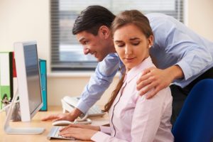 Man with hand on shoulder of uncomfortable female coworker