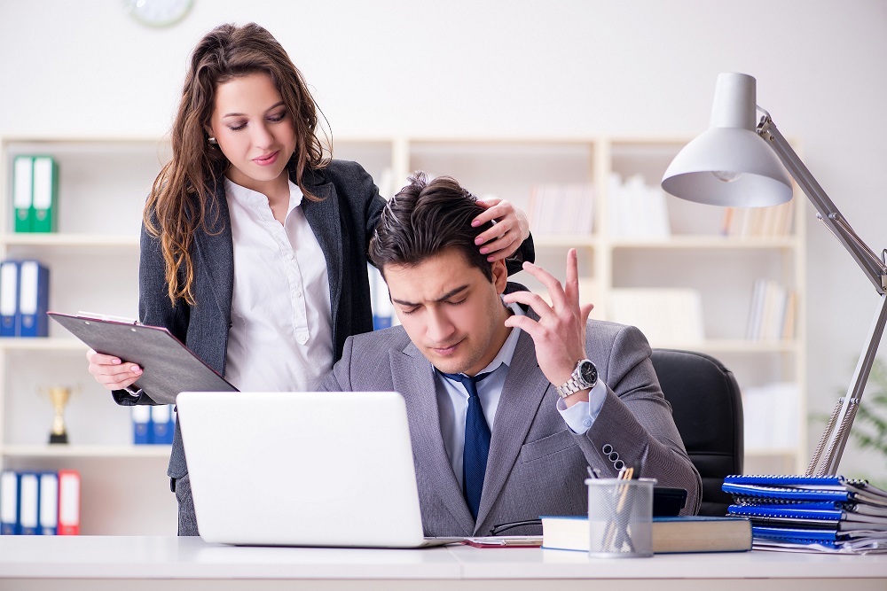 Woman touching hair of uncomfortable male coworker